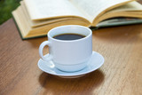 Cup of coffee and book on wooden table
