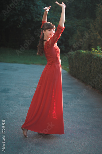 Beautiful young girl in a red long dress dancing. photo