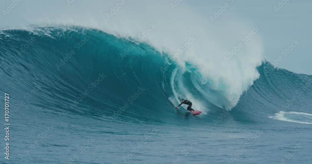 Surfer rides giant blue ocean wave. Shot on RED in 4k. Big wave surfing. Slow motion