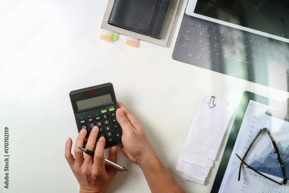 top view of businessman hand working with finances about cost and calculator and latop with mobile phone on withe desk in modern office top view of businessman hand working with finances about cost and calculator and latop with mobile phone on withe desk in modern office