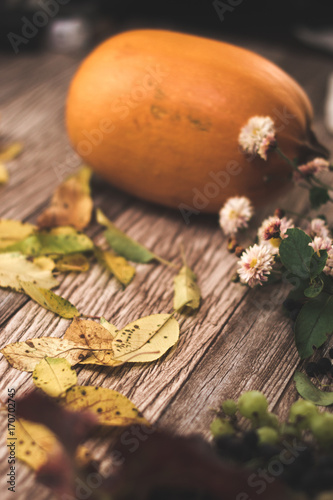 Autumn still life: pumpkin and autumn leaves on a wooden background.