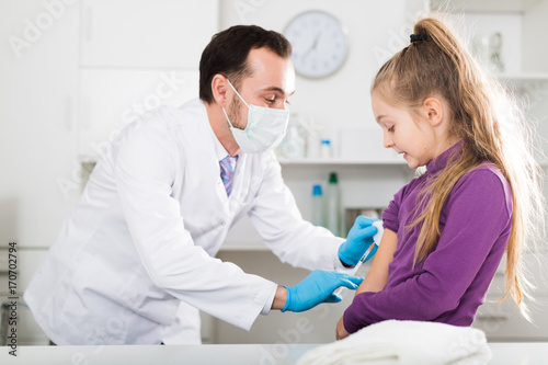 Male doctor injecting little patient