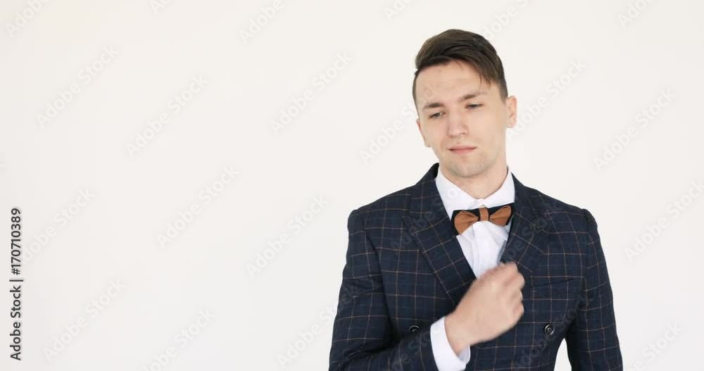 Attractive young businessman is looking at the camera. Closeup video of an attractive businessman in his 20s, wearing a blue suit and the bow tie. Against a white background. Attractive young businessman is looking at the camera. Closeup video of an attractive businessman in his 20s, wearing a blue suit and the bow tie. Against a white background.