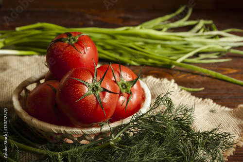red ripe tomatoes in a crib in a linen centerpiece and dark wooden background