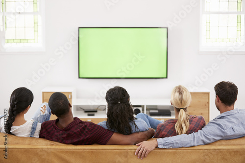 Rear View Of Group Of Young Friends Watching Television Together