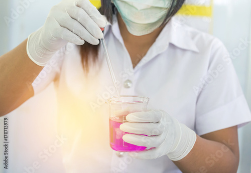scientist woman dropping pink chemical liquid with test tube glass for carrying research chemistry liquid in science laboratory research and experiment concept
