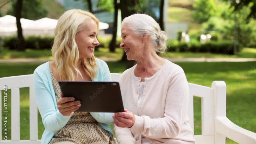 daughter with tablet pc and senior mother at park