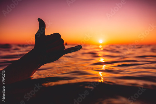 Shaka symbol and red sunset at sea. Lifestyle photo photo