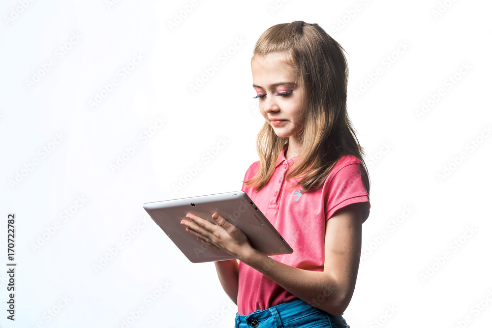 Beautiful little girl with a tablet computer in hands on a white background. Emotions of the child. Beautiful little girl with a tablet computer in hands on a white background. Emotions of the child.
