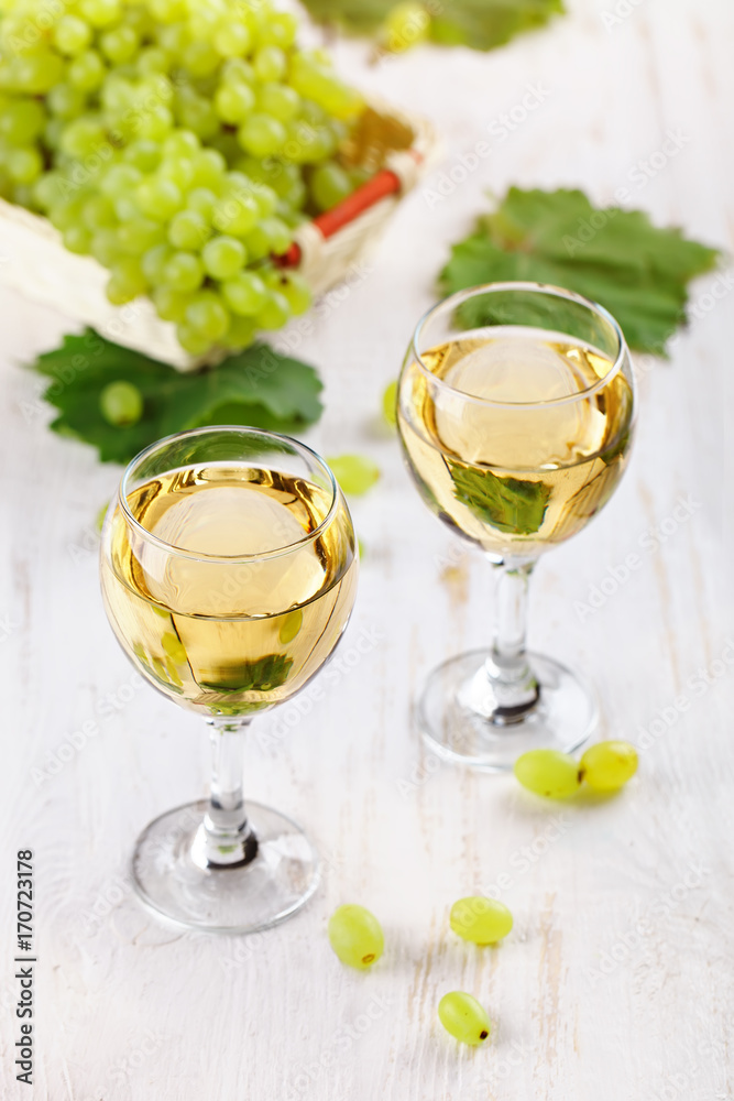 Glasses with white wine and fresh grapes on a wooden table. Glasses with white wine and fresh grapes on a wooden table.