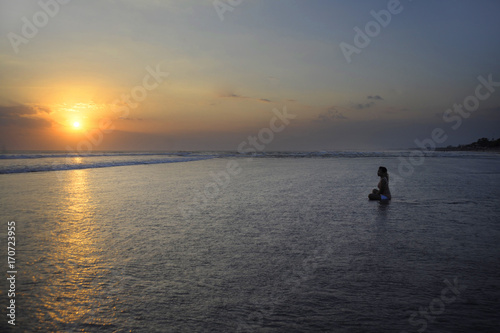 Silhouette of young beautiful asian woman sitting on sand water free and relaxed looking at the sun on sunset beach © Wordley Calvo Stock