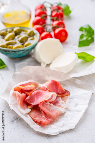 Prosciutto Olives olive oil mozzarella cheese tomatoes basil - ingredients italian or mediterranean cuisine.