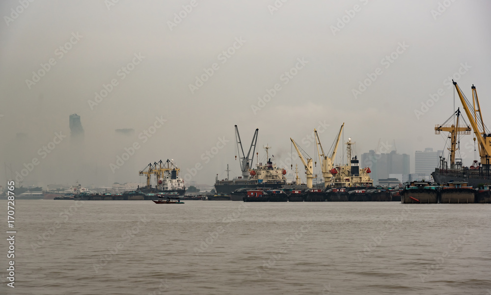 Logistics and transportation of International Container Cargo ship in a harbor for logistic import export background and transport industry with Drizzling rain and haze day.
