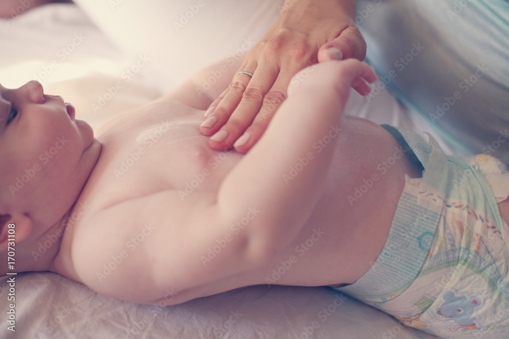 Mother with her baby by at home. Mother uses a body cream, and putting of a baby. Mother with her baby by at home. Mother uses a body cream, and putting of a baby.
