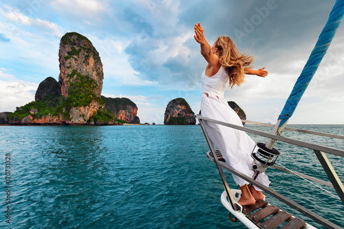 Joyful young woman portrait. Happy girl stand on deck of sailing yacht, have fun discovering islands in tropical sea on summer coastal cruise. Travel adventure, yachting with kids on family vacation.