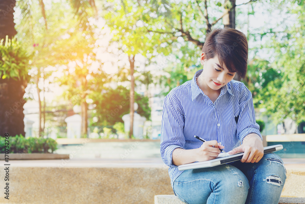 Beautiful short hair woman sitting on the floor and writing a note for outdoor working her business in the park. Beautiful short hair woman sitting on the floor and writing a note for outdoor working her business in the park.