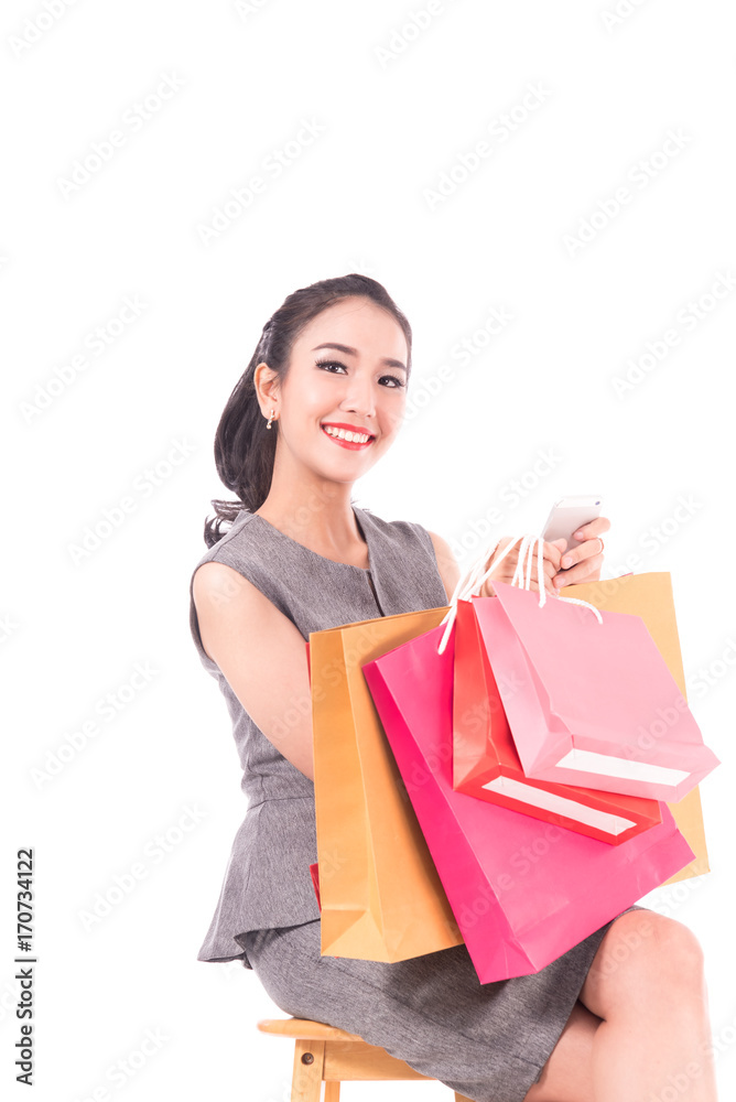 Cheerful shopping women of Asian holding bags with smart-phone isolated on white ,portrait beautiful business women in studio