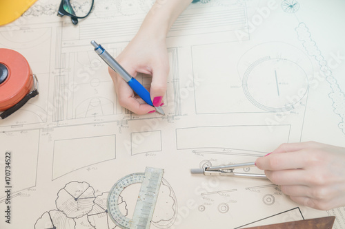 Architect drawing on a blueprint with a compass and ruler.