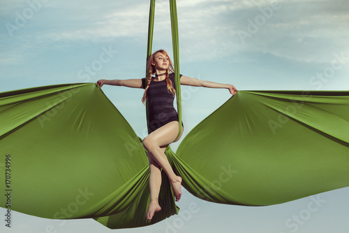 Fotografija Woman aerial acrobat performs on canvases in the sky.