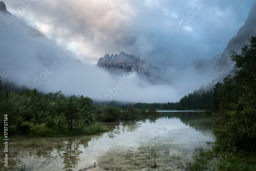 Alpine mountain lake at misty foggy morning