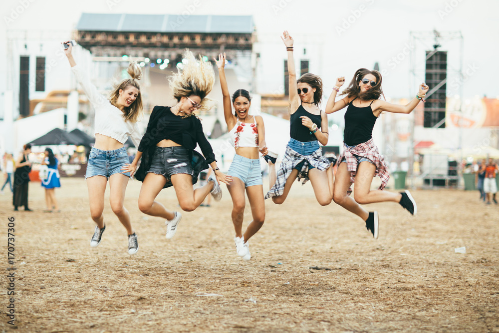 Friends jumping together on music festival - obrazy, fototapety, plakaty 