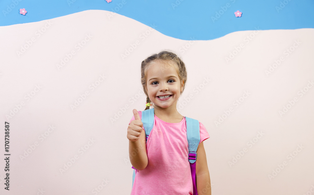 Adorable little girl with school bag showing thumbs up, copy space Adorable little girl with school bag showing thumbs up, copy space