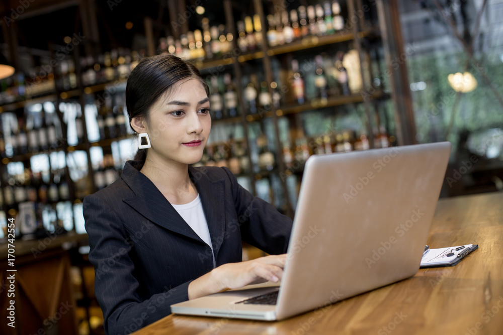 Asian Woman using laptop in restaurant with Attractive Smiling, Woman working Concept Asian Woman using laptop in restaurant with Attractive Smiling, Woman working Concept