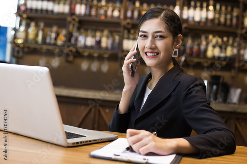 Asian Woman using Smartphone in restaurant with Attractive Smiling, Woman working Concept photo