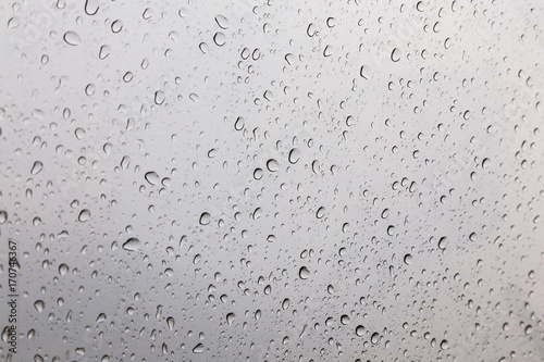 Rain drops on window glasses surface with gray sky background .Rain pattern close up of raindrops isolated on gray background.