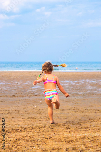 Little girl runs across the beach.