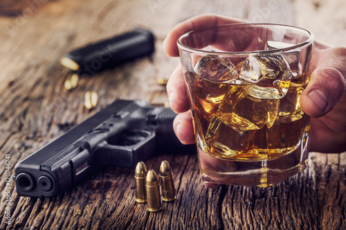 Gun and alcohol. 9mm pistol gun and cup whiskey cognac or brandy