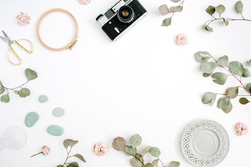 Flat lay border frame with retro camera, eucalyptus branches, plate and scissors on white background. Top view artist background with space for text.
