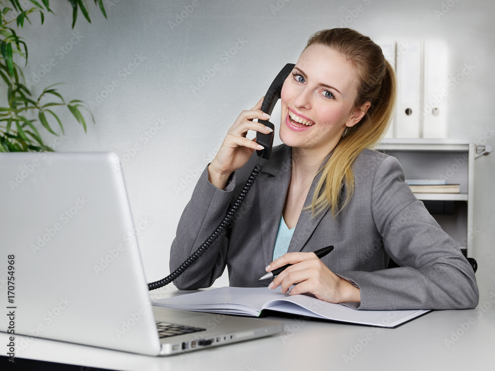 junge Frau telefoniert am Schreibtisch junge Frau telefoniert am Schreibtisch