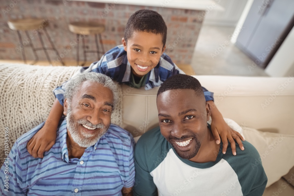 Obraz premium Smiling multi-generation family sitting together on sofa