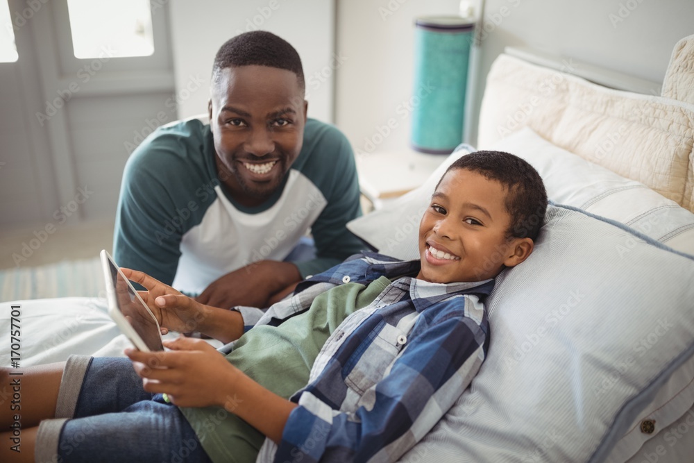 Father and son with digital tablet in bedroom - obrazy, fototapety, plakaty 