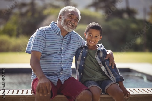 Obraz na plátne Smiling grandfather and grandson sitting together on bench