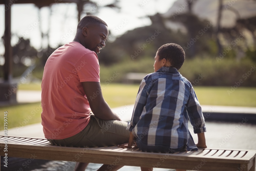 Afro american father talking to son near pool side - obrazy, fototapety, plakaty 