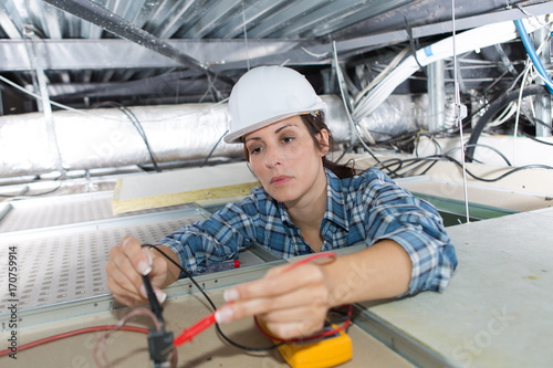 female electrician calibrating ceiling lamps photo