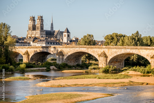 Fotografi Landscape view on the river and old arch bridge in Orleans city during the sunse