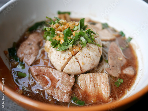 thai noddle of jumbo pork ball, pig liver, pork slide and vegetable on wooden table, hot noodle with blood pink for soup, in Thailand call Boat Noddle.