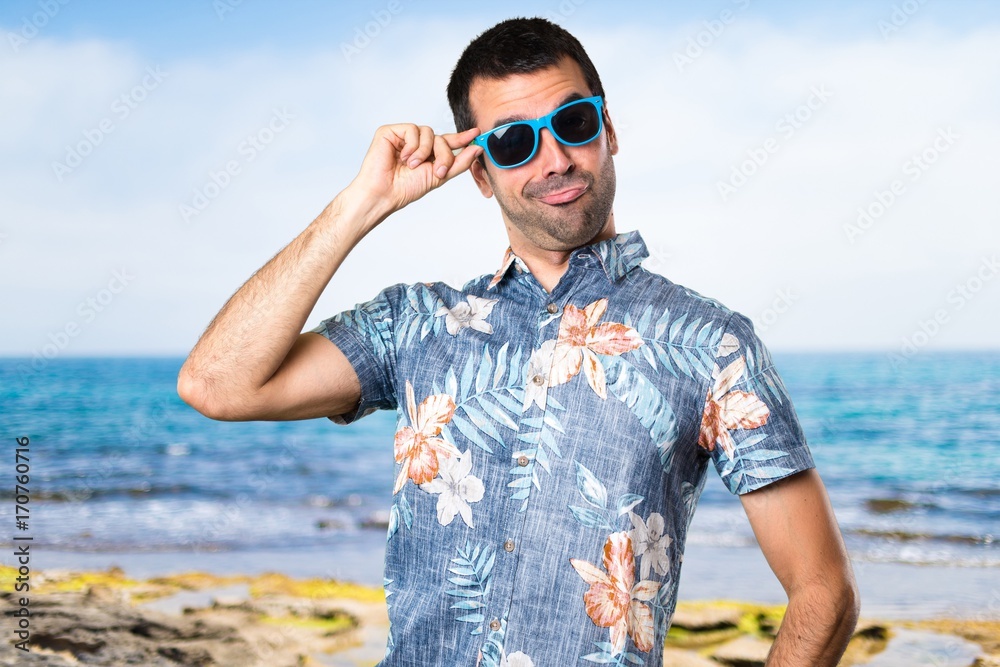 Handsome man with flower shirt with sunglasses at the beach Handsome man with flower shirt with sunglasses at the beach
