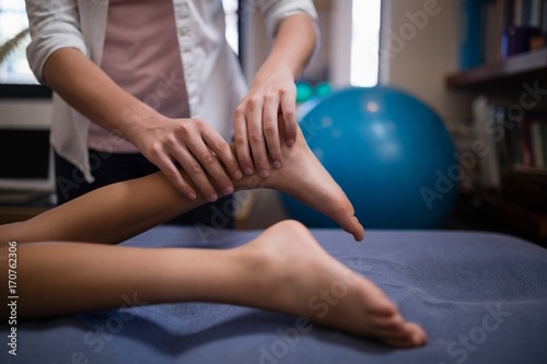 Midsection of female therapist massaging leg while boy lying on