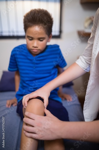 Boy looking while female therapist massaging knee © WavebreakMediaMicro