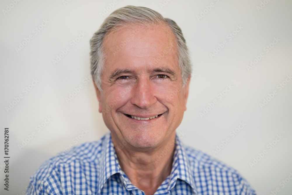 Close-up portrait of smiling senior male patient against wall Close-up portrait of smiling senior male patient against wall