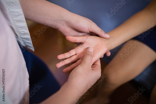 Midsection of female therapist massaging palm with boy sitting