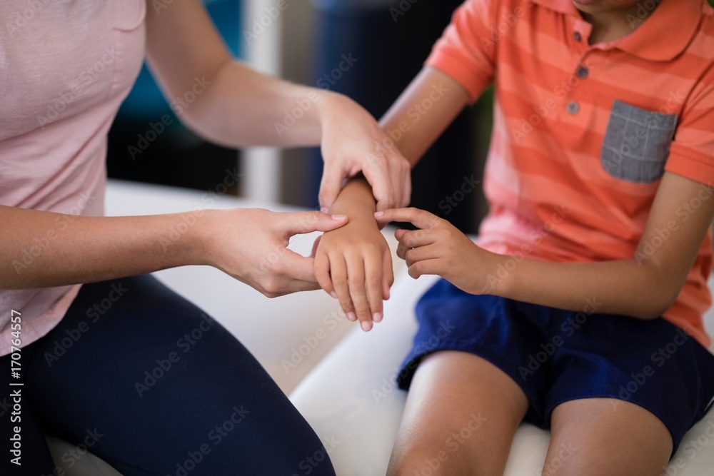 Midsection of female therapist examining hand with boy sitting Midsection of female therapist examining hand with boy sitting