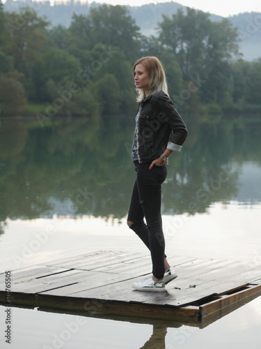 Young blonde woman on wooden pallet of water with hands in pocke