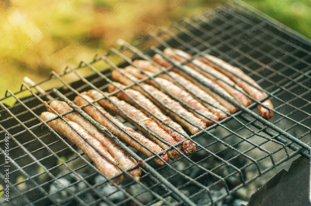close up grilled sausages on bbq in sunlight. selective focus 