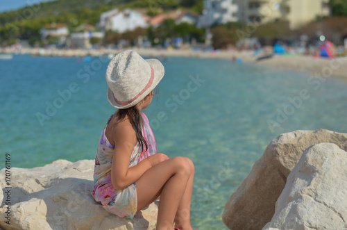 littel girl sitting at the turquoise sea
