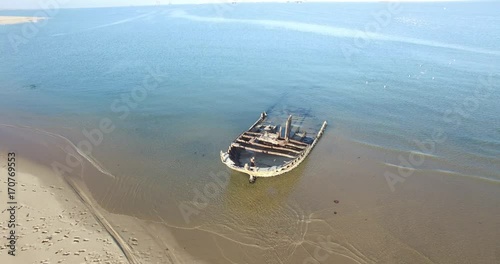 Aerial view drone video of Pelican Point Lodge and Paratus lighthouse on sand beach peninsula, shipwreck and lagoon with ocean background with ships at Namibia's Atlantic west coast